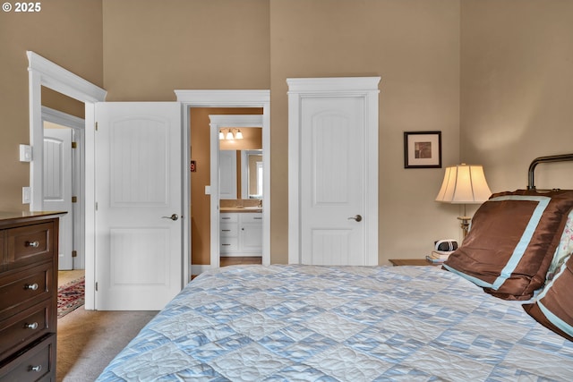 carpeted bedroom featuring a towering ceiling and ensuite bath