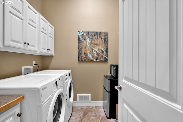 clothes washing area with cabinet space, baseboards, and washing machine and clothes dryer