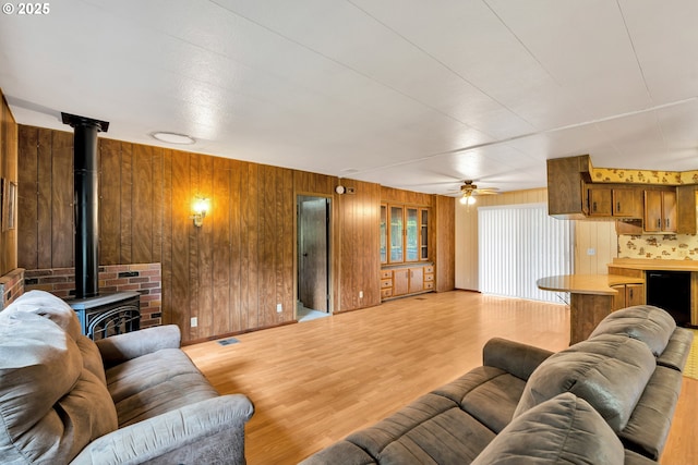 24344 NW Meacham Rd, North Plains, OR 97133 - living room with a wood stove, wooden walls, wood finished floors, and a ceiling fan