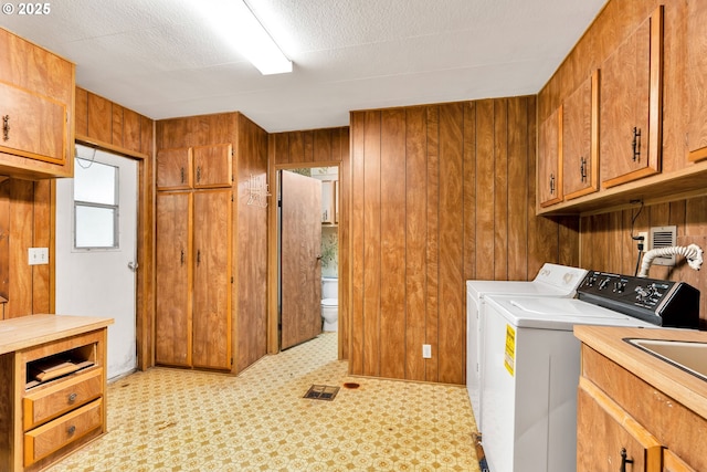 24344 NW Meacham Rd, North Plains, OR 97133 - laundry area featuring cabinet space, washer and dryer, wood walls, and light flooring