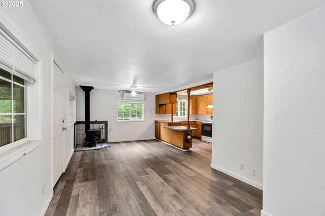 24344 NW Meacham Rd, North Plains, OR 97133 - unfurnished living room with a wood stove, dark wood-style flooring, and baseboards