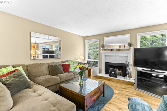 1018 S Holly Ct, Canby, OR 97013 - living room with wood finished floors, healthy amount of natural light, a tiled fireplace, and a textured ceiling