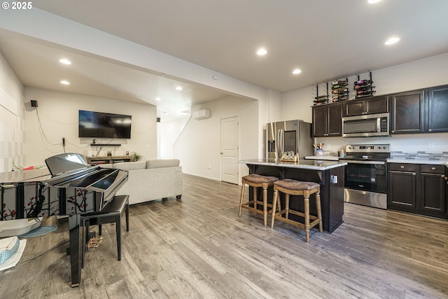 kitchen featuring light hardwood / wood-style floors, a kitchen bar, appliances with stainless steel finishes, dark brown cabinetry, and a center island