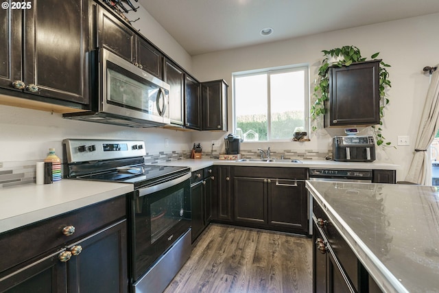 kitchen with dark brown cabinetry, appliances with stainless steel finishes, sink, and dark hardwood / wood-style floors