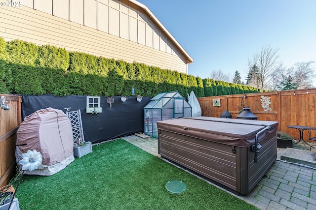 view of yard featuring a hot tub, an outdoor structure, and a patio