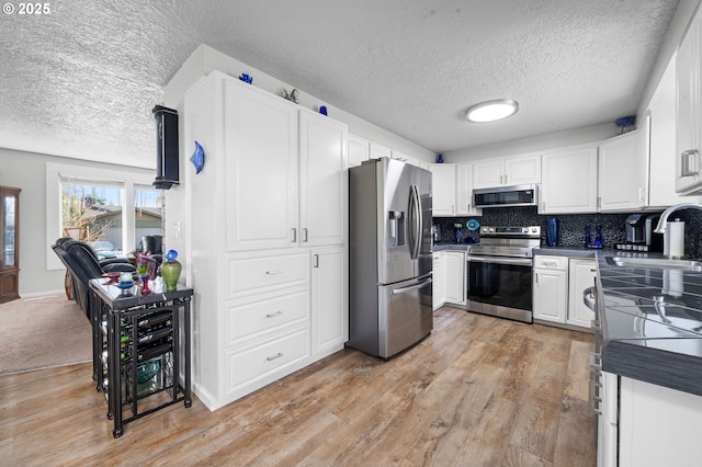 35363 Woodland Ln, Astoria, OR 97103 - kitchen with a textured ceiling, a sink, white cabinetry, and stainless steel appliances