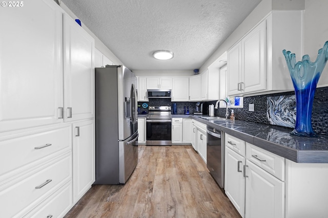35363 Woodland Ln, Astoria, OR 97103 - kitchen with light wood-style floors, tile countertops, white cabinets, a sink, and stainless steel appliances