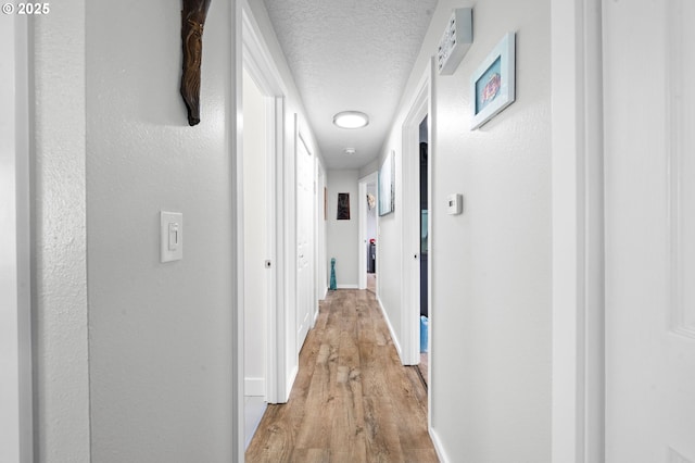 35363 Woodland Ln, Astoria, OR 97103 - hall featuring light wood-style floors, baseboards, and a textured ceiling
