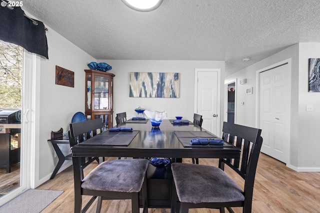 35363 Woodland Ln, Astoria, OR 97103 - dining space with a textured ceiling, baseboards, light wood-type flooring, and a wealth of natural light