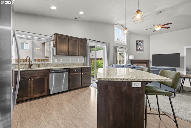 2474 Equestrian Loop S, Salem, OR 97302 - kitchen with appliances with stainless steel finishes, a kitchen island, dark brown cabinets, light wood finished floors, and a kitchen breakfast bar