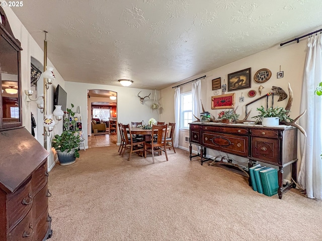 dining space with a textured ceiling and light colored carpet