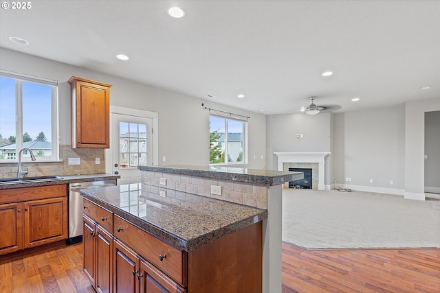 kitchen featuring sink, dishwasher, a center island, decorative backsplash, and light wood-type flooring