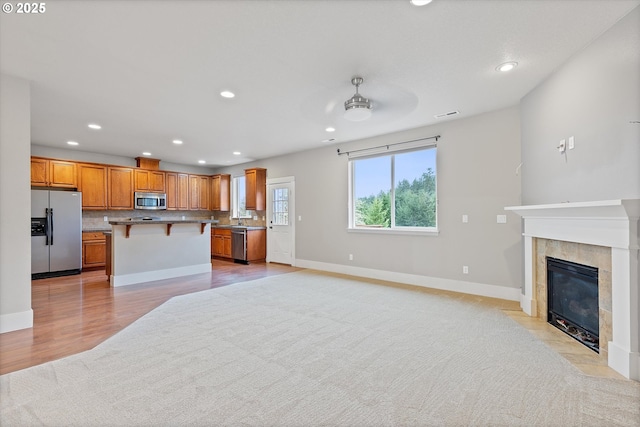 kitchen featuring a tile fireplace, tasteful backsplash, a breakfast bar area, a center island, and stainless steel appliances