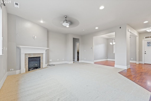 living room with a tiled fireplace, light colored carpet, and ceiling fan