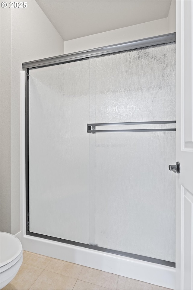 bathroom with tile patterned flooring, walk in shower, and toilet