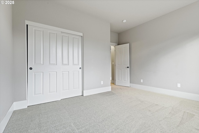 unfurnished bedroom with light colored carpet and a closet