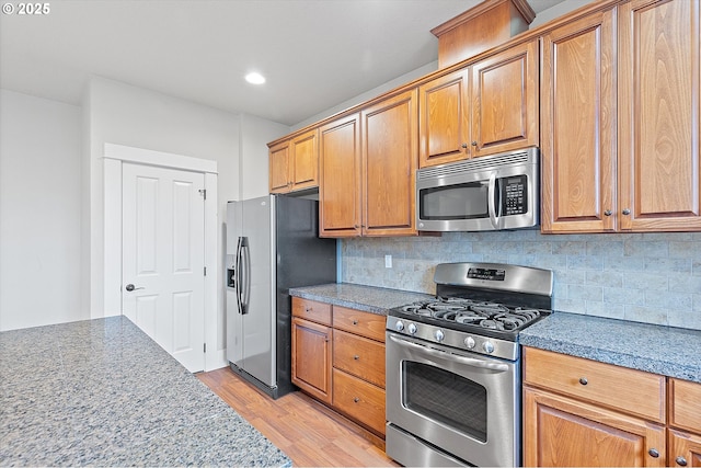 kitchen featuring appliances with stainless steel finishes, decorative backsplash, and light hardwood / wood-style flooring