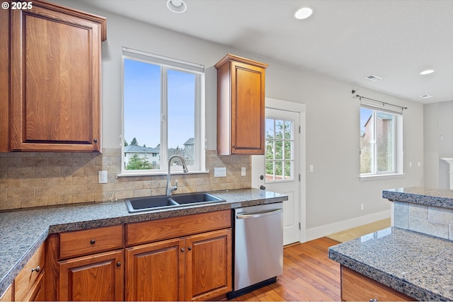 kitchen with tasteful backsplash, sink, stainless steel dishwasher, and light wood-type flooring