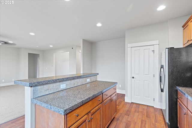 kitchen featuring a kitchen island, light wood-type flooring, and stainless steel refrigerator