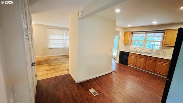 kitchen featuring sink, tasteful backsplash, dark hardwood / wood-style floors, light stone countertops, and black appliances