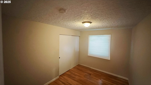 unfurnished room with hardwood / wood-style flooring and a textured ceiling