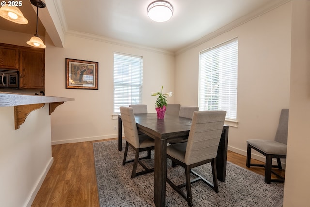 dining space with light wood-style flooring, baseboards, and crown molding