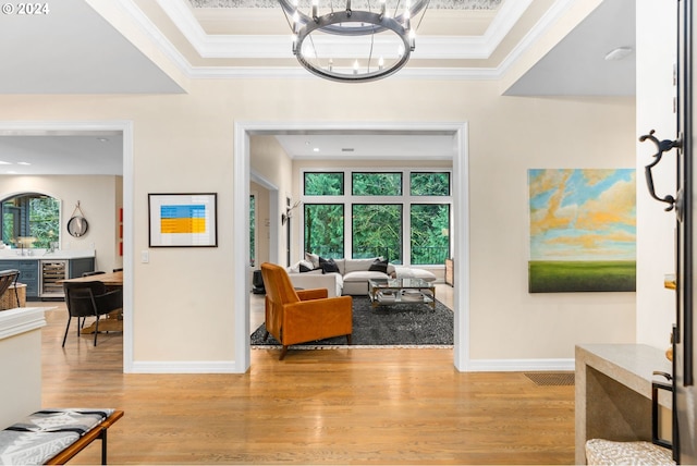 interior space with ornamental molding, light hardwood / wood-style floors, a chandelier, and beverage cooler