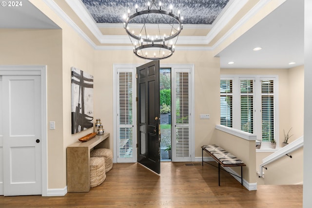 foyer with crown molding, hardwood / wood-style floors, and a notable chandelier