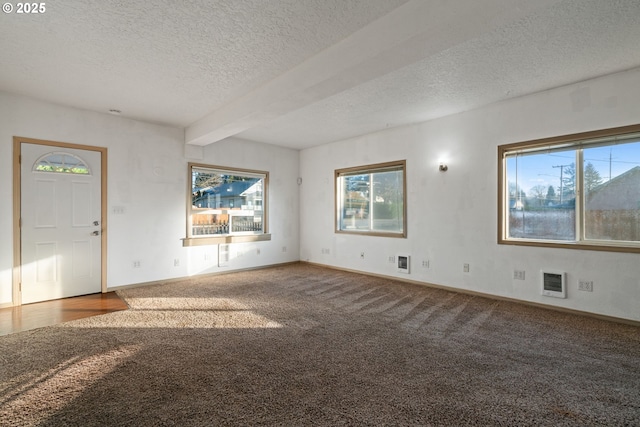 unfurnished living room featuring beam ceiling, carpet, and a textured ceiling