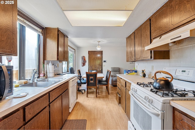 8670 SW Indian Hill Ln, Beaverton, OR 97008 - kitchen featuring white appliances, light wood finished floors, light countertops, brown cabinets, and under cabinet range hood