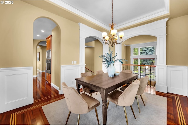 dining space with a chandelier, wainscoting, dark wood finished floors, and crown molding