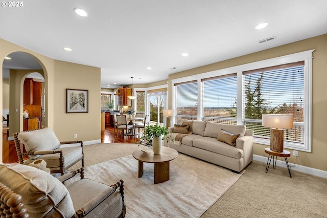 living area featuring baseboards, arched walkways, and recessed lighting