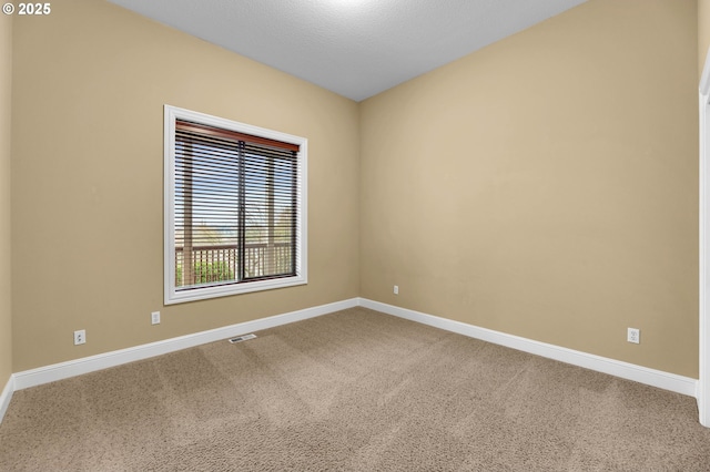 unfurnished room with a textured ceiling, carpet floors, and baseboards