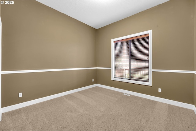 empty room with carpet flooring, visible vents, and baseboards