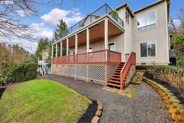 rear view of property featuring stairway, a lawn, and a balcony