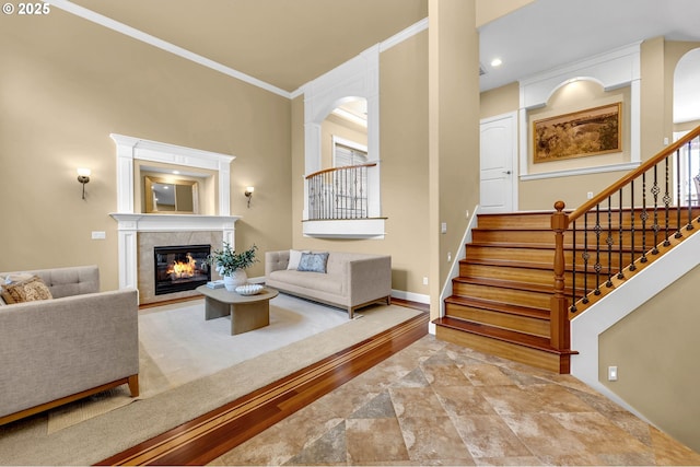 living room with ornamental molding, baseboards, stairway, and a tiled fireplace