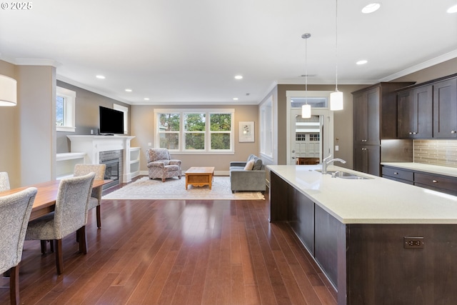 kitchen with sink, dark brown cabinets, crown molding, and pendant lighting