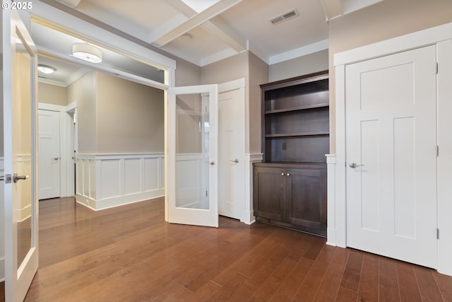 unfurnished bedroom with crown molding, dark hardwood / wood-style floors, and french doors