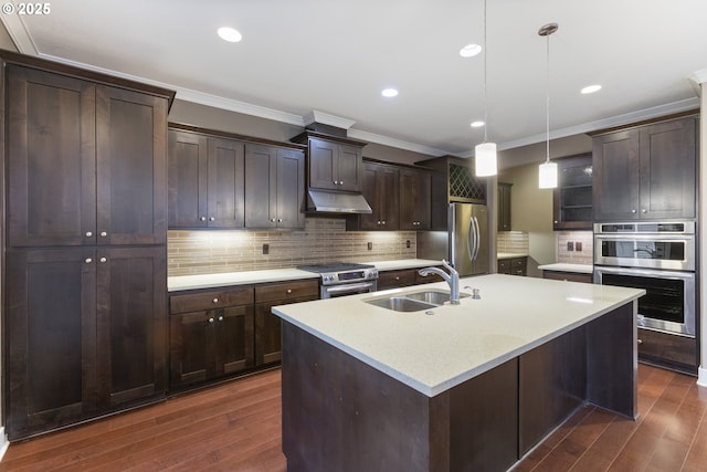 kitchen with appliances with stainless steel finishes, sink, decorative light fixtures, backsplash, and an island with sink