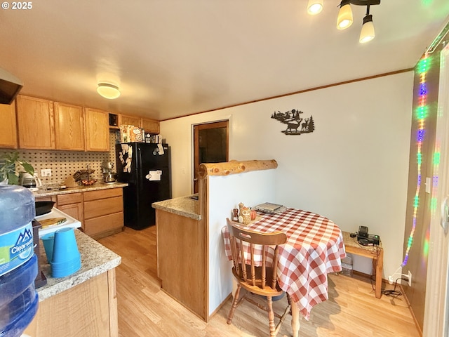 kitchen with light countertops, backsplash, light wood-style flooring, ornamental molding, and freestanding refrigerator