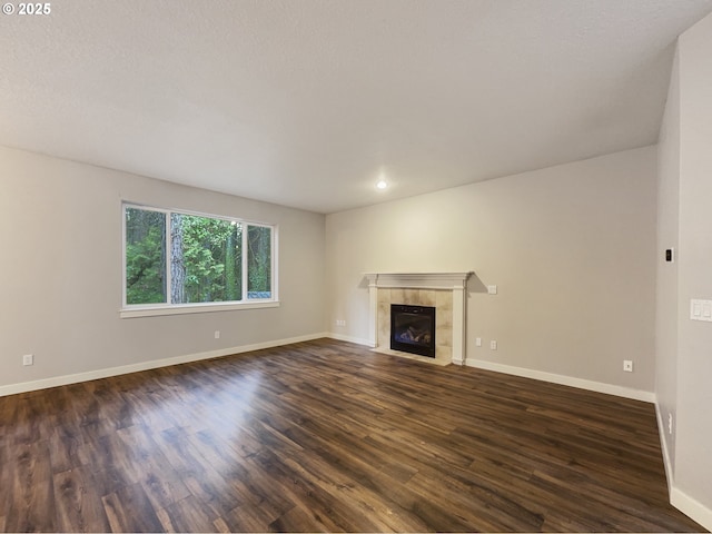 unfurnished living room featuring dark wood-type flooring and a tiled fireplace