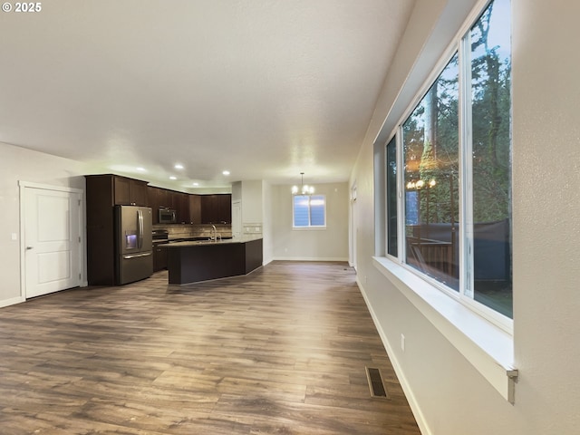 kitchen with dark brown cabinetry, pendant lighting, a chandelier, appliances with stainless steel finishes, and hardwood / wood-style flooring