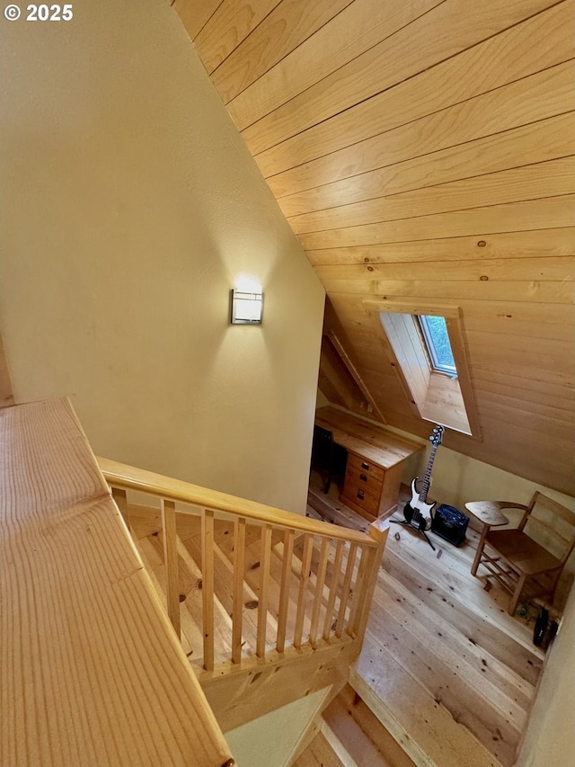 additional living space featuring vaulted ceiling with skylight, light hardwood / wood-style flooring, and wooden ceiling