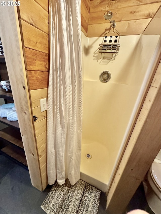 bathroom with curtained shower, wooden walls, and toilet