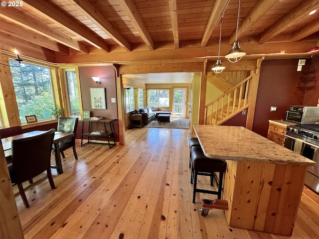 kitchen with pendant lighting, wood ceiling, light hardwood / wood-style flooring, stainless steel gas stove, and beam ceiling