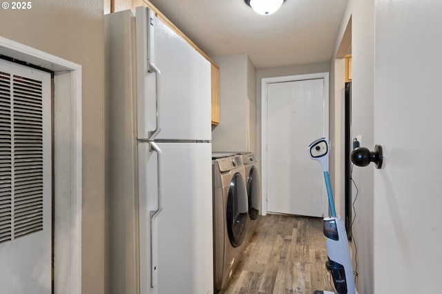 clothes washing area with hardwood / wood-style flooring, cabinets, and separate washer and dryer