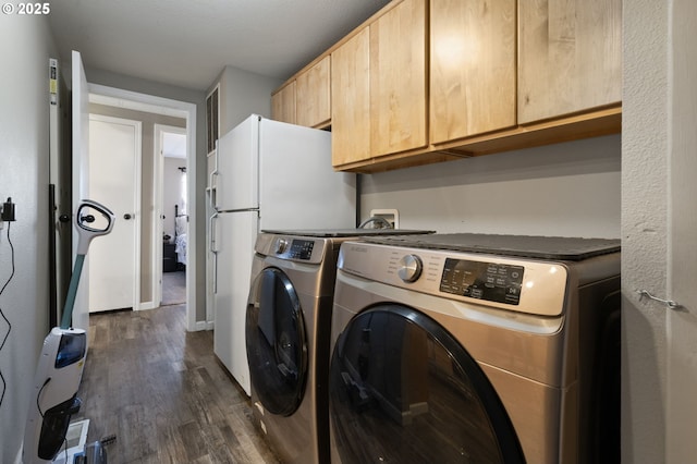 clothes washing area with cabinets, dark hardwood / wood-style floors, and washer and clothes dryer