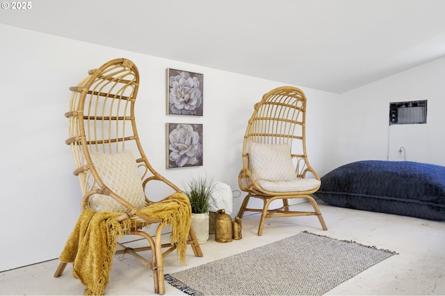 sitting room featuring lofted ceiling and an AC wall unit