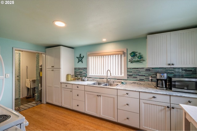 kitchen with stainless steel microwave, a sink, decorative backsplash, light wood finished floors, and recessed lighting
