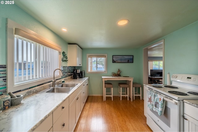 kitchen featuring white electric stove, a sink, light wood-style flooring, light countertops, and recessed lighting